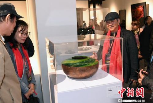 参展艺术家、台湾工艺发展协会常务理事彭坤炎(前右一)介绍其参展作品《春之颂》创作过程。　记者刘可耕 摄